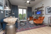 Located at 2641 E College Ave in Decatur, Georgia, this thoughtfully designed single-floor residence combines contemporary style with functional living. The open-concept kitchen is a standout feature, showcasing white shaker cabinetry, stainless steel appliances, a tiled backsplash, light hardwood flooring, and a central island with pendant lighting — ideal for both everyday cooking and entertaining. The living area exudes an eclectic, curated character, with sliding glass doors opening to a private balcony with outdoor views, a ceiling fan, and bold industrial-style shelving accented by neon signage. The space offers multiple bedrooms, each with its own personality. One features serene neutral tones, carpet flooring, and a large window with natural tree views, while another makes a dramatic statement with deep blue accent walls, built-in shelving, and stylish pendant lighting. Both bathrooms are elegantly appointed with dual under-mount sinks, dark countertops, white cabinetry, backlit mirrors, and large-format tile flooring. One bathroom also includes a glass-enclosed walk-in shower. Throughout the residence, an emphasis on natural light, carefully chosen finishes, and distinctive design details creates a cohesive and sophisticated living environment.