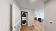 Located on Harvard Ave in Seattle's vibrant Capitol Hill neighborhood, this thoughtfully designed 2-bedroom, 1-bathroom unit offers a clean, modern aesthetic throughout its efficiently laid-out floor plan. The kitchen serves as a standout feature, boasting two-toned cabinetry with white upper cabinets and dark lower cabinets, a subway tile backsplash, white quartz countertops, a large central island, and a full suite of stainless steel appliances including a French door refrigerator, electric range, microwave, and dishwasher. Light wood-style flooring runs through the main living areas, complementing the bright, neutral palette. The primary bedroom features sliding barn-style doors leading to a dedicated closet and is finished with warm wood flooring, while the second bedroom offers plush carpet and a window with natural light. The bathroom is finished with a clean walk-in glass shower, modern vanity with dark hardware, and dark tile flooring. A hallway closet houses a stacked in-unit washer and dryer, adding everyday convenience. A wall-mounted mini-split system ensures efficient climate control. The overall ambiance is contemporary, clean, and move-in ready.