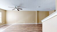 This two-story home offers a functional and comfortable layout across two floors. The main level features an open-concept living, dining, and kitchen area, creating a connected and versatile space ideal for everyday living. The kitchen is equipped with warm wood cabinetry, white appliances including a range, dishwasher, and refrigerator, complemented by light countertops and durable wood-look flooring that extends throughout the main living areas. Ceiling fans provide added comfort in the living spaces, while natural light filters in through windows fitted with blinds.

Upstairs, three bedrooms offer carpeted flooring, ceiling fans, and natural light from well-placed windows. The primary bedroom provides a generous footprint with dedicated closet space. Two full bathrooms serve the home, each featuring a tub-shower combination, wood cabinetry for storage, and wood-look flooring. Four closets distributed throughout the home offer abundant storage solutions.

The warm, neutral beige tones carried consistently across walls on both floors lend the home a cohesive and inviting ambiance. The overall layout is practical and efficient, making effective use of every level to deliver a comfortable living environment suitable for a range of occupants.
