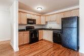 Located at 57 E Centre St in Nutley, New Jersey, this single-floor unit offers a functional and well-appointed layout designed for comfortable everyday living. Warm hardwood flooring flows consistently throughout the living areas and bedrooms, lending the space a cohesive and inviting character.

The open-concept living area is generously sized, bathed in natural light from a sliding glass door that leads to an exterior access point, complemented by vertical blinds for adjustable privacy. A dedicated entry door adds a welcoming focal point to the room.

The kitchen is efficiently designed in an L-shaped configuration, featuring light maple cabinetry with brushed nickel hardware, dark granite countertops, and black appliances including a gas range, built-in microwave, dishwasher, and refrigerator. Hardwood flooring continues seamlessly into this space.

The bedrooms offer comfortable proportions with continued hardwood flooring, neutral walls, and ample natural light through window blinds. At least one bedroom includes access to a closet, providing useful storage.

The bathroom is finished with large-format ceramic tile flooring, white cabinetry, a dark granite vanity top, a wall-mounted light fixture, and a framed mirror, creating a clean and polished aesthetic throughout.