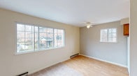 This single-floor residence offers a practical and comfortable layout designed for everyday living. The main living area is bright and welcoming, featuring light hardwood-style flooring, a ceiling fan, and a wide bank of windows that invite generous natural light and views of the surrounding neighborhood. A baseboard heating system runs along the perimeter, ensuring consistent warmth throughout. An adjoining carpeted area provides additional living or dining space, with neutral-toned walls and a clean, open feel.

The kitchen is equipped with warm wood-toned cabinetry, ample counter space, and includes a full-size refrigerator and electric range. A window above the counter brings in natural light, making the space feel open and functional.

The bedroom is generously sized, finished with plush carpeting and softly painted walls that create a calm, restful environment. A large walk-in closet with double shelving and rod systems provides substantial storage. The bathroom features a full-size soaking tub with a shower, accented by neutral tile surroundings and a window for natural ventilation.

Throughout the space, consistent neutral tones, carpeted bedrooms, and easy-care hard flooring in common areas create a cohesive, move-in-ready environment suited for a variety of lifestyles.