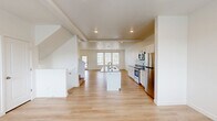 Located at 7299 North Locust Avenue in Eagle Mountain, Utah, this three-story home offers a well-organized layout spread across three distinct levels. The entry-level ground floor houses an attached garage with a automatic opener, utility rooms, and additional storage, providing a practical foundation for the home.

The main living floor serves as the social hub of the residence, featuring an open-concept kitchen and living area finished with light hardwood-style flooring. The kitchen is equipped with stainless steel appliances, white shaker cabinetry, a central island with a sink and dark countertop, and recessed lighting, creating a clean, modern aesthetic. A half bathroom on this level adds everyday convenience.

The upper floor contains all three bedrooms, including a generously sized primary bedroom with dual windows, a ceiling fan, and plush carpeting. The additional bedrooms are finished with neutral carpet and bright white walls. Four closets and multiple hallways provide ample storage throughout.

Externally, the stucco and stone facade fits cohesively within the neighborhood streetscape. The backyard features a mix of lawn, rock landscaping, and a dramatic natural boulder retaining wall, with a balcony overhead adding outdoor living space.