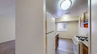 Located at 18215 Lost Knife Cir in Montgomery Village, MD, this one-bedroom, one-bathroom residence offers a well-organized, single-floor layout across a compact yet functional footprint. The galley-style kitchen is efficiently designed with warm honey-toned wood cabinetry lining both sides, granite-look countertops, a gas range, dishwasher, and a white refrigerator. Wood-look flooring and flush-mount ceiling lighting give the kitchen a clean, practical feel, while a window allows natural light to filter in. The living area is open and airy, finished with wall-to-wall carpeting and neutral tones throughout. A sliding glass door with vertical blinds anchors the main living space, providing outdoor access and additional natural light. The bedroom is a comfortable size, featuring plush carpet, multiple closets with bi-fold doors offering generous storage, and a dedicated second closet for added convenience. The bathroom includes a white vanity with a single sink, ample counter space, a large mirror, and a multi-bulb vanity light fixture. A connecting hallway with additional storage ties the rooms together seamlessly. Overall, the space presents a clean, move-in ready environment with a neutral palette well-suited for easy personalization.