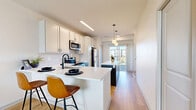 Located at 14843 Orchard Pkwy in Westminster, CO, this two-story, two-bedroom, two-bathroom residence is thoughtfully designed with a clean, modern aesthetic. The main level features an open-concept layout where the kitchen, dining, and living areas flow seamlessly together. The kitchen is a standout, boasting white shaker cabinetry with a white subway tile backsplash, stainless steel appliances, a large central island with bar seating, and pendant lighting. Light hardwood-style flooring runs throughout the main level, complementing the bright, neutral palette. The dining area leads to a private balcony through sliding glass doors, filling the space with natural light. The living room is warm and inviting, featuring large windows and ample room for comfortable furnishings. A pantry and dedicated laundry area add to the functional layout. Upstairs, the two bedrooms offer plush carpeting and generous closet space. The primary bedroom features large windows with outdoor views and connects to a private en-suite bathroom with a white vanity and matte black hardware. A second full bathroom with a tub-shower combination serves the additional bedroom. Five closets throughout ensure abundant storage across both floors.