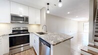 Located at 400 W Saint Elmo Rd in Austin, TX, this two-story, 2-bedroom, 2-bathroom home is thoughtfully designed across two equally sized floors. The main level features an open-concept layout combining the living room, dining area, and kitchen. The kitchen is a standout, showcasing white shaker cabinetry, a white subway tile backsplash, granite countertops, a peninsula island with an undermount sink, stainless steel appliances including a range, microwave, and dishwasher, and warm wood-look flooring throughout. Pendant lighting adds a modern touch overhead. Upstairs, both bedrooms are carpeted and bathed in natural light from windows with outdoor tree views. Each bedroom includes a ceiling fan and closet storage. The bathrooms are finished with granite-topped vanities, wood-look flooring, and a tiled tub-and-shower combination featuring classic white subway tiles and brushed nickel fixtures. A dedicated laundry area and hallway complete the upper level. The home's clean, neutral palette and updated finishes create a cohesive and functional living environment throughout.