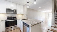 Located at 400 W Saint Elmo Rd in Austin, TX, this two-story, 2-bedroom, 2-bathroom home is thoughtfully designed across two equally sized floors. The main level features an open-concept layout combining the living room, dining area, and kitchen. The kitchen is a standout, showcasing white shaker cabinetry, a white subway tile backsplash, granite countertops, a peninsula island with an undermount sink, stainless steel appliances including a range, microwave, and dishwasher, and warm wood-look flooring throughout. Pendant lighting adds a modern touch overhead. Upstairs, both bedrooms are carpeted and bathed in natural light from windows with outdoor tree views. Each bedroom includes a ceiling fan and closet storage. The bathrooms are finished with granite-topped vanities, wood-look flooring, and a tiled tub-and-shower combination featuring classic white subway tiles and brushed nickel fixtures. A dedicated laundry area and hallway complete the upper level. The home's clean, neutral palette and updated finishes create a cohesive and functional living environment throughout.