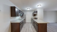 Located at 949 Golf Course Rd in Crystal Lake, Illinois, this well-appointed single-floor residence offers two bedrooms and two bathrooms within a thoughtfully designed layout. The galley-style kitchen is a standout feature, showcasing rich dark espresso cabinetry, granite countertops, stainless steel appliances including a refrigerator and built-in microwave, and light wood-look flooring that ties the space together cohesively. The bright living room is highlighted by large sliding glass doors fitted with vertical blinds, providing abundant natural light and direct access to an outdoor patio with views of the surrounding greenery. Both bedrooms are comfortably sized, featuring plush carpet flooring and windows that bring in natural light. The spacious primary bedroom includes a dedicated closet, while one bathroom features direct closet access for added convenience. Both bathrooms are finished with clean, neutral tones, dark vanity cabinetry, and a full tub-shower combination. Additional spaces include a utility room and closet, rounding out the functional layout. Neutral gray walls and consistent flooring choices throughout create a clean, modern aesthetic that is move-in ready.