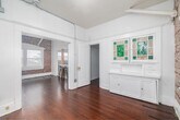 Located at 15 Paloma Ave in the heart of Venice, Los Angeles, this one-bedroom, one-bathroom unit blends classic character with thoughtful updates. Rich, warm hardwood floors flow throughout the main living areas, complemented by crisp white walls and exposed conduit detailing that lend an industrial-chic aesthetic. The open layout connects the living room to the kitchen, where a framed pass-through with a wood-topped breakfast bar and two bar stools creates an inviting casual dining spot. The kitchen is well-appointed with gray shaker cabinets, a marble-style tile backsplash, stone-look tile flooring, a stainless steel farmhouse sink, and a gas range — all bathed in natural light from a window overlooking the surroundings. Exposed brick walls add warmth and texture to the living area, which also features a ceiling fan. The bedroom offers a cozy, dedicated retreat with its own closet. A compact bathroom is accessible via a short staircase, adding a unique architectural touch. The space makes efficient use of every square foot, offering a functional and characterful home in one of Los Angeles' most sought-after neighborhoods.