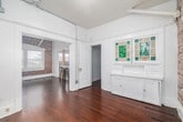 Located at 15 Paloma Ave in the heart of Venice, Los Angeles, this one-bedroom, one-bathroom unit blends classic character with thoughtful updates. Rich, warm hardwood floors flow throughout the main living areas, complemented by crisp white walls and exposed conduit detailing that lend an industrial-chic aesthetic. The open layout connects the living room to the kitchen, where a framed pass-through with a wood-topped breakfast bar and two bar stools creates an inviting casual dining spot. The kitchen is well-appointed with gray shaker cabinets, a marble-style tile backsplash, stone-look tile flooring, a stainless steel farmhouse sink, and a gas range — all bathed in natural light from a window overlooking the surroundings. Exposed brick walls add warmth and texture to the living area, which also features a ceiling fan. The bedroom offers a cozy, dedicated retreat with its own closet. A compact bathroom is accessible via a short staircase, adding a unique architectural touch. The space makes efficient use of every square foot, offering a functional and characterful home in one of Los Angeles' most sought-after neighborhoods.