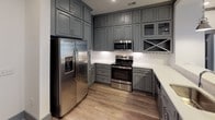 Located at 4124 Providence Road in Charlotte, NC, this single-floor unit delivers a well-appointed, contemporary living environment with consistent design elements throughout. The open-concept living and dining area is anchored by warm wood-look plank flooring, recessed lighting, and bold dark crown molding that frames the crisp white walls. A set of glass-paneled French doors floods the space with natural light and opens directly onto a private balcony, providing views of the surrounding community.

The kitchen is a standout feature, outfitted with floor-to-ceiling gray shaker-style cabinetry, white quartz countertops, a classic subway tile backsplash, and a full suite of stainless steel appliances including a French door refrigerator, electric range with over-the-range microwave, and dishwasher. A peninsula with pendant lighting serves as both a prep area and casual dining space, connecting seamlessly to the main living area.

The bedrooms feature plush carpeting, large windows with horizontal blinds, and ceiling fans for added comfort. The bathrooms are finished with striking marble-look porcelain tile flooring and wall surrounds, gray cabinetry with white countertops, glass-enclosed showers, and soaking tubs, conveying a refined, spa-like aesthetic throughout.