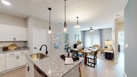 Located at 6080 Tides Way in Myrtle Beach, South Carolina, this single-floor residence offers a thoughtfully designed open-concept layout that seamlessly connects the kitchen, dining, and living areas. Light wood-style flooring flows throughout, complementing a neutral color palette that gives the space a bright, coastal-inspired feel.

The kitchen is a standout feature, equipped with crisp white shaker cabinetry, granite countertops, a subway tile backsplash, and stainless steel appliances. A central island with an undermount sink and pendant lighting serves as both a functional workspace and a casual dining spot.

The living area is calm and inviting, with large windows that draw in natural light and a ceiling fan overhead. A separate dining space connects the kitchen to the living room, creating a natural flow ideal for entertaining.

The bedrooms are generously proportioned, each featuring light-filled windows with blinds and curtains, ceiling fans, and light wood flooring. One bedroom features a serene blue accent wall, while another offers a walk-in closet. The bathrooms include granite-topped vanities with white cabinetry; the primary bath features a dual-sink vanity, while the secondary bath includes a tub-shower combination.