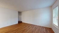 This two-story unit at The Villager in Memphis, Tennessee, offers a practical and well-organized layout spread evenly across two floors. The main level features two living areas, both finished with warm hardwood-style flooring that extends throughout. The front living room receives natural light through multiple windows and includes a ceiling fan, while a second living space at the rear opens through French doors, allowing additional outdoor light and views. The kitchen is centrally equipped with rich dark-stained cabinetry, light granite-style countertops, a peninsula island, and black appliances including an electric range and dishwasher, all set atop the same wood-style flooring.

The upper floor houses the four bedrooms, each carpeted and featuring built-in closets with shelving. The spacious primary bedroom offers a generous footprint with ample closet storage. The full bathroom includes a tub-shower combination with built-in shelving, a wood-topped vanity with dark cabinetry, and hardwood-style flooring. Textured ceilings are consistent throughout the home, contributing to a clean, uniform aesthetic across both levels.