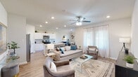 This single-story home offers a thoughtfully designed open-concept layout that seamlessly connects the living, dining, and kitchen areas. The living room is bright and welcoming, featuring recessed lighting, a ceiling fan, light wood-look flooring, and large windows dressed with sheer curtains that invite abundant natural light. A stylish media console and glass coffee table complement the neutral, contemporary furnishings.

The kitchen is well-equipped with white shaker-style cabinetry, granite countertops, a subway tile backsplash, and stainless steel appliances including a gas range and over-the-range microwave. A central island provides additional workspace and casual seating.

A hallway connects the private sleeping quarters to the main living space. The bedrooms are comfortably sized, with ceiling fans and neutral walls. One bedroom features a distinctive decorative wall panel with geometric molding detailing, adding a custom design element. The primary suite includes an en-suite bath with access to a spacious walk-in closet with wrap-around shelving and hanging rods.

The bathrooms feature tile flooring and clean, neutral finishes. A dedicated laundry room accommodates a full-size washer and dryer with overhead shelving and direct exterior door access, adding everyday convenience to this well-rounded home.