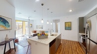 Located at 2500 Summer Lee Dr in Rockwall, Texas, this single-floor residence offers a thoughtfully designed open-concept layout with modern finishes throughout. The kitchen serves as a central hub, anchored by a generous granite-topped island with a built-in sink and pendant lighting overhead. Gray cabinetry, stainless steel appliances — including a refrigerator, range, and microwave — and warm wood-look flooring complete the space with a clean, contemporary aesthetic. The kitchen flows seamlessly into the living area, which features a ceiling fan, recessed lighting, and a sliding glass door that opens to a private patio, flooding the space with natural light. The bedroom is carpeted for comfort, with ample natural light from a large window and access to a spacious walk-in closet lined with full perimeter shelving and hanging rods. Two bathrooms are finished with granite countertops, gray vanity cabinetry, large mirrors, and wood-look flooring. The primary bathroom features a double-sink vanity and a shower-tub combination, while the secondary bath includes a single-sink vanity. Throughout the residence, crisp white walls and consistent finishes create a cohesive, bright atmosphere well-suited for modern living.