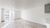 Located at 1601 N Poinsettia Place in Los Angeles, this thoughtfully designed one-bedroom, one-bathroom unit offers a clean, modern aesthetic across a single floor. The open-concept living and dining area is filled with natural light streaming through floor-to-ceiling vertical blind-covered windows, illuminating the light wood-tone flooring and crisp white walls. Recessed lighting adds a contemporary touch throughout the space.

The kitchen is a functional highlight, featuring gray shaker-style cabinetry, a light subway tile backsplash, a white quartz peninsula with an undermount stainless steel sink, and stainless steel appliances including a refrigerator. The layout opens directly to the living and dining area, making it ideal for everyday use.

The bedroom offers a comfortable footprint with the same light hardwood-style flooring, a ceiling vent for climate control, and access to closet space. Three closets provide ample storage throughout the unit.

The bathroom is elegantly finished with large-format marble-look tile on both the floors and walls, a glass-enclosed shower, a sage green vanity with brushed gold hardware, and a clean white countertop, creating a polished, spa-like atmosphere.

A hallway connects the rooms efficiently, completing this well-appointed and move-in ready Los Angeles residence.