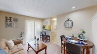 This thoughtfully designed one-bedroom, one-bathroom unit in Metairie, Louisiana makes excellent use of its compact footprint across a single floor. A welcoming entry hallway with tile flooring leads into the main living area, where plush carpet, a textured ceiling, and a wall-unit HVAC system create a cozy atmosphere. The living room accommodates a full seating arrangement and features a sliding glass door that floods the space with natural light and provides outdoor access. Adjacent to the living room, a defined dining nook with recessed lighting offers an intimate space for meals. The kitchen features white cabinetry, a full suite of appliances including a refrigerator, electric range, microwave, and dishwasher, along with a breakfast bar that connects to the main living area for added convenience. The bedroom is carpeted and includes a ceiling fan with light fixture, a mirrored sliding-door closet, and a vanity area with built-in sink and cabinetry just outside the bathroom. A dedicated laundry room houses a stacked washer and dryer unit alongside built-in shelving for added storage. Throughout the unit, neutral warm tones and consistent finishes create a cohesive and comfortable living environment.