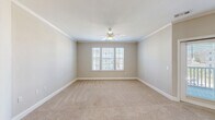 Located at 12000 Sweet Pl in Charleston, SC, this well-appointed single-floor residence offers two bedrooms, two bathrooms, and two closets within a thoughtfully designed layout. The open-concept kitchen and living area serves as the heart of the home, showcasing rich hardwood flooring, crown molding, and pendant lighting. The kitchen is equipped with stainless steel appliances, granite countertops, a subway tile backsplash, white shaker-style cabinetry, and a peninsula with an undermount sink — ideal for both cooking and entertaining. Natural light flows freely through multiple windows fitted with horizontal blinds, brightening the connected living area. Both bedrooms are carpeted and feature ceiling fans, crown molding, and ample natural light from large windows. The spacious primary bedroom includes a dedicated walk-in closet with wire shelving for organized storage. The primary bathroom is a standout, offering dual sinks set in granite countertops, white cabinetry, hardwood floors, a glass-enclosed shower, and elegant vanity lighting. The second bathroom provides additional convenience. Throughout the residence, a neutral color palette and consistent finishes create a clean, cohesive aesthetic that is both functional and inviting.