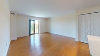 This single-floor residence at 1400 Worcester Rd in Framingham, Massachusetts, offers a well-designed layout with consistent warm-toned hardwood flooring and neutral wall finishes throughout. The open-concept kitchen is a standout feature, equipped with stainless steel appliances including a gas range, over-the-range microwave, and refrigerator. It showcases rich wood lower cabinets paired with sleek white upper cabinetry and clean white countertops, with an island providing additional workspace and casual seating. The kitchen opens directly to a generously sized living area, which benefits from natural light and access to a private balcony through sliding glass doors that frame views of the surrounding wooded landscape. The bedroom features warm hardwood floors, a large window with scenic tree-line views, crown molding, and a built-in closet with shelving and integrated drawers for ample storage. The bathroom is finished with marble-style tile flooring, a white vanity with a mirrored medicine cabinet, and a full tub-shower combination. An additional utility or flex space provides built-in white cabinetry and counter space on marble-style tile flooring, offering practical storage and workspace. The overall ambiance is clean, bright, and move-in ready.