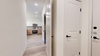 This single-floor residence showcases a clean, modern design highlighted by light wood-tone luxury vinyl flooring that flows consistently throughout the space. The kitchen serves as a central feature, equipped with stainless steel appliances including a range, microwave, and dishwasher. Cabinetry combines crisp white upper cabinets with warm wood-toned lower cabinets, complemented by a gray tile backsplash and a peninsula with pendant lighting and a built-in sink, offering both functionality and style.

The living area is bright and open, featuring a ceiling fan, exterior door access, and windows fitted with blinds that allow natural light to filter in. The bedrooms are well-proportioned, each finished with the same continuous flooring and ceiling fans for added comfort.

The primary bathroom is a standout, featuring a dual-sink vanity with wood-toned cabinetry and white countertops, a walk-in tiled shower with marble-style tile, and a dedicated walk-in closet with built-in shelving. A secondary bathroom mirrors the aesthetic with a tub-shower combination finished in the same striking marble-style tile and matte black fixtures, maintaining a cohesive and contemporary feel throughout.