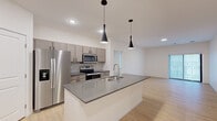 This well-designed single-story home offers 2 bedrooms and 3 bathrooms within a thoughtfully laid-out floor plan. The open-concept kitchen and living area serves as the heart of the home, anchored by a central island with a dark quartz countertop, an integrated sink, and sleek pendant lighting. Gray cabinetry lines the kitchen walls, complemented by stainless steel appliances including a refrigerator, range, and microwave. Light hardwood-style flooring flows seamlessly throughout the main living areas, creating a warm, cohesive aesthetic.

The two bedrooms feature soft carpeting and windows that allow natural light to fill each room. The spacious primary bedroom includes a walk-in closet outfitted with wire shelving for ample storage. The bathrooms are finished with light wood vanities, dark countertops, and modern fixtures, with marble-style tile flooring featured in one of the full bathrooms.

A dedicated laundry room houses a full-size washer and includes utility connections for added convenience. Additional highlights include a hallway that connects all rooms efficiently, a dedicated closet for extra storage, and a living area with access to an outdoor space through a large sliding glass door with vertical blinds. The overall ambiance is clean, contemporary, and move-in ready.