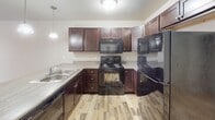 Located at 1233 Tom Sawyer Trail in Harrisburg, South Dakota, this single-floor residence offers a well-organized layout designed for comfortable everyday living. The kitchen serves as a central highlight, featuring rich dark-stained cabinetry, light laminate countertops, and a full suite of black appliances including a range, microwave, dishwasher, and refrigerator. A peninsula with a double-basin sink and pendant lighting above adds both function and visual appeal, while wood-look flooring grounds the space with a warm, durable finish.

The living area transitions seamlessly from the kitchen, featuring neutral carpet and a sliding glass door that opens to a private balcony, filling the room with natural light. The bedrooms are carpeted and neutrally toned, offering a calm atmosphere, with closets equipped with wire shelving systems for organized storage.

Two full bathrooms serve the home, each featuring dark wood vanities with light countertops and wood-look flooring. One bathroom includes a shower-only configuration, while the other offers a full tub-shower combo. A dedicated laundry area accommodates a full-size washer and dryer with overhead shelving for added storage convenience.