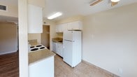 Located at 7051 Bowling Dr in Sacramento, California, this single-story unit offers a functional and well-organized layout with a variety of finishes throughout. The entry area features light tile flooring that flows seamlessly into the kitchen, which is equipped with white cabinetry, granite-look countertops, a coil-top electric range, a full-size refrigerator, a dishwasher, and ample upper and lower storage. A peninsula counter separates the kitchen from the adjacent living areas, providing a convenient transitional space.

The open living and dining area is finished with warm wood-style laminate flooring and includes a ceiling fan. A sliding glass door leads to a private patio, offering views of a landscaped outdoor area enclosed by wood fencing, allowing natural light to fill the space.

The bedrooms are carpeted and generously sized, each with sliding mirror-door closets and windows that overlook greenery outside. The bathroom features tile flooring, a white vanity with a granite-look countertop, a large wall mirror, and a tiled tub and shower surround. A hallway connects the main living areas to the bedrooms and bathroom, with in-unit laundry hookups also present. The overall palette of warm neutrals and clean white finishes lends a bright, move-in-ready atmosphere throughout.