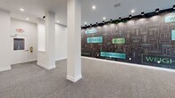 Located at 74 Church St in Flemington, NJ, this single-floor commercial space is designed with a clear fitness and wellness identity. The open-plan layout offers a versatile, unobstructed floor area finished with durable speckled carpet tile throughout, making it well-suited for gym, studio, or wellness-related use. Structural columns are cleanly integrated into the space, finished in crisp white to complement the bright, neutral walls and white baseboard trim.

A defining feature of the space is its bold, large-scale graphic wall mural stretching across a prominent interior wall. Rendered in dark tones with teal and green accents, the mural displays fitness-themed words and phrases — including "Wellness," "Fitness," "Body," "Weight," "Muscles," and "Determination" — creating an energizing and motivational ambiance throughout.

Lighting consists of recessed ceiling fixtures supplemented by track-mounted spotlights that illuminate the feature wall with precision. At the front of the space, floor-to-ceiling black-framed storefront windows flood the interior with natural light and provide clear sightlines to the exterior streetscape, enhancing visibility and openness. The overall design is modern and clean, offering a polished, move-in-ready environment for a fitness or wellness-oriented business.