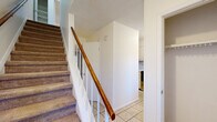 Located at 902 Gum Branch Rd in Jacksonville, North Carolina, this two-story home offers a practical and straightforward layout spread across two floors. The main level features a welcoming living room with plush carpeting, a front-facing window that invites natural light and views of the surrounding greenery, and a tiled entryway. The kitchen is equipped with white cabinetry, a double-basin stainless steel sink beneath a window, ample countertop space, and a dishwasher, providing a clean and functional workspace. A staircase with a warm wood handrail and carpeted treads connects the two floors, complemented by multiple hallways that support smooth circulation throughout the home. The full bathroom features a tub-shower combination with chrome fixtures and a white vanity with storage. Upstairs, two carpeted bedrooms offer comfortable retreats. The spacious primary bedroom includes a ceiling fan with light fixture, a window for natural light, and a built-in closet with shelving. The secondary bedroom is equally well-lit and features its own closet. Additional closet storage is available on both levels, adding to the home's practicality. The overall aesthetic is clean and neutral, with light-toned walls throughout.