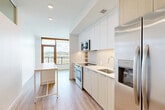 Located at 600 Howard Road SE in Washington, DC, this efficiently designed one-bedroom, one-bathroom residence offers a thoughtful layout across a single floor. The entrance leads into a bright, open corridor with light wood-style flooring and crisp white walls that carry throughout the space.

The combined kitchen and dining area is a standout feature, outfitted with stainless steel appliances including a refrigerator with ice dispenser, electric range, built-in microwave, and dishwasher. Two-toned cabinetry in white and warm wood tones pairs with light quartz countertops, providing ample storage and prep space. A kitchen island with integrated drawers adds functionality to the layout. Floor-to-ceiling windows at the end of the kitchen flood the space with natural light and offer open outdoor views, with direct access to a private patio.

The living room provides a comfortable gathering area, while the bedroom features warm wood flooring and two closets for generous storage. The bathroom is finished with large-format tile, a soaking tub with shower, and a floating wood-toned vanity topped with white quartz beneath an illuminated mirror. Additional practicalities include a dedicated laundry area and a utility room, making this a fully functional and well-appointed residence.