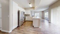 Located at 210 Summit Blvd in Broomfield, Colorado, this well-appointed three-bedroom, two-bathroom single-floor residence offers a thoughtfully designed layout with modern finishes throughout. Rich wood-style flooring flows through the main living areas, complemented by neutral tones that create a bright and welcoming ambiance.

The heart of the home is an open-concept kitchen and living area. The kitchen is outfitted with white cabinetry, quartz countertops, a tile backsplash, stainless steel appliances, and a peninsula with a built-in sink — ideal for both everyday cooking and entertaining. The adjacent living room features a corner fireplace and large windows that invite natural light.

A dedicated dining area and a combined kitchen-living space provide flexible options for daily living. The hallway connects the main areas to the private quarters, where three carpeted bedrooms offer a comfortable retreat. The generously sized primary bedroom includes its own closet. Two well-finished bathrooms feature white vanities with quartz countertops, wood-style flooring, large mirrors, and tub-shower combinations. An in-unit laundry area adds everyday convenience. Three closets throughout the home provide ample storage.