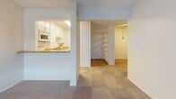 Located at 2404 Nutwood Ave in Fullerton, California, this single-floor unit offers a practical and well-organized layout suited for comfortable everyday living. The open living area is finished with neutral-toned carpet throughout, creating a cohesive and understated aesthetic across the space. A large window with vertical blinds allows natural light to fill the room, contributing to a bright and airy atmosphere. Wall-mounted heating and air conditioning units provide climate control throughout the unit.

The kitchen is thoughtfully positioned with a pass-through opening that connects it to the living area, promoting an open feel. It features warm-toned countertops, white cabinetry with modern hardware, a double stainless steel sink, a gas range, and an over-the-range microwave — offering a complete and functional cooking space.

The bedroom areas are carpeted and quietly lit, each benefiting from windows that bring in natural light and outdoor views of the surrounding neighborhood. The rooms provide a clean, neutral canvas well-suited for personalization.

The bathroom is finished with tile flooring and includes a single-sink vanity with warm countertops, white cabinetry, a large mirror, and a full-size tub and shower combination with chrome fixtures. A built-in shelving unit near the entryway adds additional storage and organizational flexibility to the overall layout.