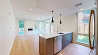 Located at 703 Whitney Ave in New Haven, CT, this contemporary 2-bedroom, 2-bathroom residence showcases a clean, modern design with high-quality finishes throughout. The single-floor layout centers around an open-concept kitchen and living area, where light hardwood floors, recessed lighting, and floor-to-ceiling windows create a bright and welcoming atmosphere. The living room features a sleek built-in fireplace and expansive windows that overlook a private, fenced backyard with lush greenery—ideal for relaxing or entertaining.

The kitchen is anchored by a large center island with a white quartz countertop, undermount sink, and wood-toned cabinetry, complemented by striking pendant lights. Stainless steel appliances, including a gas range, microwave, and refrigerator, are paired with white subway tile backsplash and white upper cabinets for a polished look. A tall window allows natural light to fill the cooking space.

Both bedrooms are well-proportioned, featuring hardwood flooring, ample closet space—including a double-door closet in the primary—and clean white walls. The primary bathroom offers a sophisticated feel with large-format tile flooring, stone-surround walls, and a frameless glass walk-in shower. Additional conveniences include in-unit laundry and multiple hallway closets for generous storage throughout.