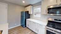 Located at 265 Seneca Dr in Syracuse, NY, this freshly renovated single-floor home offers a clean, modern aesthetic throughout. The interior is unified by light-toned luxury vinyl plank flooring and a soft neutral gray color palette, creating a bright and cohesive atmosphere from room to room.

The open-concept living and dining area is airy and well-lit, benefiting from large windows that invite natural light and offer views of the surrounding neighborhood. Recessed lighting adds a contemporary touch to the space. A white kitchen island with a pendant light and undermount sink anchors the kitchen, which is outfitted with crisp white shaker cabinets, white countertops, a stainless steel range, and a full-size refrigerator. A window above the counter adds additional natural light to the cooking space.

The bedrooms are generously proportioned and well-appointed, with neutral walls, recessed lighting, and ample closet space. One bedroom features dual windows on adjacent walls, flooding the room with natural light and views of the outdoors.

The bathroom is a standout feature, finished with large-format marble-look tile on both the floors and walls, including a fully tiled tub surround. A floating vanity with a vessel sink, a large mirror, and a window complete this refined space. The overall design reflects thoughtful, move-in-ready renovations throughout.