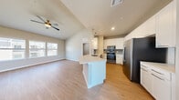 This thoughtfully designed 3-bedroom, 2-bathroom home features an open-concept layout that seamlessly connects the kitchen and living area. The kitchen is well-appointed with white shaker cabinetry, gray subway tile backsplash, quartz countertops, stainless steel appliances including a range, microwave, dishwasher, and refrigerator, and a central island with pendant lighting. The adjacent living area benefits from vaulted ceilings, a ceiling fan, and large windows that fill the space with natural light. Light wood-look flooring runs throughout the main living areas, while plush carpet adds comfort to the bedrooms. The spacious primary bedroom features vaulted ceilings, a ceiling fan, and direct access to a generous walk-in closet equipped with multi-tiered wire shelving. The two additional bedrooms offer wood-look flooring and windows with neighborhood views. The bathrooms are finished with white cabinetry, quartz countertops, and a subway tile tub-surround. One bathroom conveniently houses an in-unit washer and dryer. A carpeted staircase with a white handrail provides additional access within the home. Neutral tones and clean finishes throughout create a bright and cohesive living environment.