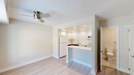 This two-story home in Newark, Delaware offers a clean, modern aesthetic across two thoughtfully laid-out floors. The main level features light-toned hardwood-style flooring throughout the open living and dining area, which is brightened by a large window fitted with blinds and complemented by a ceiling fan. A staircase with a sleek metal railing connects both levels, adding a contemporary architectural touch. The kitchen is efficiently designed with high-gloss white cabinetry, a subway tile backsplash, white appliances including a refrigerator, electric range, microwave, and dishwasher, as well as a peninsula with a white countertop that opens to the main living space. A half bathroom on the main floor provides added convenience. Upstairs, the spacious primary bedroom features plush carpeting and a large walk-in closet with built-in shelving. The second bedroom is equally comfortable, also carpeted, with a standard closet featuring a hanging rod. Both bedrooms share access to a well-appointed full bathroom, finished with large-format tiles, a tub-shower combo with glass enclosure, and a white vanity with modern hardware. A dedicated laundry room on the upper level houses a full-size Whirlpool washer and dryer with overhead wire shelving. Neutral tones and clean finishes give the entire home a bright, move-in-ready appeal.