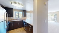 This single-floor residence offers a thoughtfully designed layout with comfortable living spaces throughout. The kitchen is a functional highlight, featuring rich dark espresso cabinetry with brushed nickel hardware, granite-style countertops, a double stainless steel sink, and a dishwasher. A large circular overhead light fixture and a window overlooking lush greenery provide both brightness and a pleasant view while cooking.

The living room is generously sized, anchored by a tile-surround fireplace and enhanced by abundant natural light streaming through large windows and a sliding glass door that opens to a private balcony with outdoor views. A ceiling fan adds comfort, and soft neutral carpeting extends throughout the space.

The bedrooms are quiet and well-proportioned, each with plush carpeting and large windows with vertical blinds. The primary bedroom includes a mirrored sliding-door closet with built-in shelving, offering practical storage. Neutral warm-toned walls create a calm, versatile ambiance across all rooms.

The bathroom is clean and well-finished, featuring dark cabinetry with a granite-style vanity top, a single sink, a full tub-shower combination, and tile flooring. Consistent design finishes throughout the space tie the interior together cohesively.