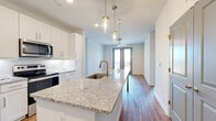 Located at 3256 Buford Hwy in Duluth, Georgia, this single-floor residence presents a modern, thoughtfully designed layout with contemporary finishes throughout. The open-concept kitchen serves as a central highlight, featuring a large granite-topped island with an undermount sink and brushed gold faucet, illuminated by stylish pendant lighting. White shaker cabinetry extends to the ceiling, complemented by a white tile backsplash and a full suite of stainless steel appliances, including a side-by-side refrigerator with ice maker, electric range, and microwave. Rich hardwood-style flooring flows through the main living areas, leading toward sliding glass doors that open onto a private balcony, where a ceiling fan adds comfort to the space.

Carpeted bedrooms provide a softer feel, with large windows fitted with blinds offering views of the surrounding neighborhood. A generously sized walk-in closet with wire shelving and hanging rods provides ample storage. The bathrooms are finished with granite vanity countertops, undermount sinks, white shaker cabinetry, and marble-style tiled shower surrounds, creating a clean, polished aesthetic. Additional rooms with hardwood-style flooring offer flexible use. Overall, the space conveys a bright, modern ambiance with quality finishes.