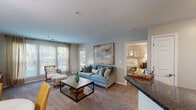 This single-floor residence at 9210 Appleford Cir in Owings Mills, Maryland, offers a thoughtfully designed layout that flows seamlessly from room to room. The living area is a welcoming focal point, featuring plush carpeting, neutral walls, and a large bank of windows that frame lush greenery outside, filling the space with abundant natural light. A door provides direct outdoor access, further enhancing the connection to the surrounding landscape.

Adjacent to the living area, a dedicated dining space accommodates a full table setting beneath a stylish pendant light, while a coordinating sitting area adds additional functionality. The kitchen is well-equipped with dark cabinetry, granite-style countertops, stainless steel appliances including a gas range, built-in microwave, dishwasher, and refrigerator, all set atop light hardwood-style flooring.

The two bedrooms are carpeted and generously sized, each offering large windows with outdoor views and ample room for substantial furniture. Both bathrooms maintain a consistent design aesthetic, featuring dark vanity cabinetry, granite-style countertops, wood-style flooring, and tub-shower combinations, providing a cohesive and polished finish throughout the residence.