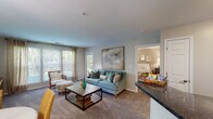 This single-floor residence at 9210 Appleford Cir in Owings Mills, Maryland, offers a thoughtfully designed layout that flows seamlessly from room to room. The living area is a welcoming focal point, featuring plush carpeting, neutral walls, and a large bank of windows that frame lush greenery outside, filling the space with abundant natural light. A door provides direct outdoor access, further enhancing the connection to the surrounding landscape.

Adjacent to the living area, a dedicated dining space accommodates a full table setting beneath a stylish pendant light, while a coordinating sitting area adds additional functionality. The kitchen is well-equipped with dark cabinetry, granite-style countertops, stainless steel appliances including a gas range, built-in microwave, dishwasher, and refrigerator, all set atop light hardwood-style flooring.

The two bedrooms are carpeted and generously sized, each offering large windows with outdoor views and ample room for substantial furniture. Both bathrooms maintain a consistent design aesthetic, featuring dark vanity cabinetry, granite-style countertops, wood-style flooring, and tub-shower combinations, providing a cohesive and polished finish throughout the residence.