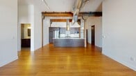 Located on the third floor of a historic building in downtown Spokane, Unit 306 at 826 West Sprague Avenue masterfully combines industrial heritage with modern living. The open-concept living area showcases soaring ceilings with exposed ductwork, original heavy timber beams, and warm bamboo hardwood flooring that flows throughout the main living spaces. Striking arched windows framed by original brick walls flood the rooms with natural light and offer views of the surrounding downtown cityscape.

The kitchen is a standout feature, offering a generous island with a white quartz countertop, rich dark-wood cabinetry, stainless steel appliances including a gas range and refrigerator, a classic white subway tile backsplash, and pendant lighting that complements the industrial aesthetic. The galley-style layout provides ample prep and storage space.

The primary bathroom features floor-to-ceiling large-format tile, a walk-in shower with a built-in bench, a dual-sink vanity with white countertops, and refined chrome fixtures. A secondary bathroom includes a tiled tub-shower combination and a single vanity. Additional conveniences include an in-unit laundry room with a full-size washer and dryer. The carpeted bedroom benefits from its own arched brick window, continuing the building's historic character.