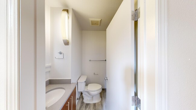 Baño con inodoro, lavabo, suelo de madera, espejo, luz y toallero. - 540 Leavenworth Street