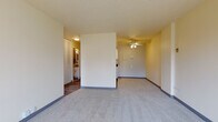 This single-floor residence at 2233 N Summit Ave in Milwaukee's vibrant East Side neighborhood offers a well-organized and functional layout. The spacious living area is finished with plush carpet, blue-accented baseboards, and a ceiling fan, creating a comfortable and airy atmosphere. A large window allows natural light to fill the room while offering views of the surrounding urban greenery and cityscape.

The kitchen is efficiently designed, featuring white cabinetry with dark countertops, a white tile backsplash, track lighting, and white appliances including a range and refrigerator. The kitchen transitions seamlessly into the living space, making it ideal for everyday living.

The bedroom is generously sized, carpeted, and equipped with a ceiling fan and a window that frames outdoor views of neighboring architecture and mature trees. A louvered bifold closet door provides practical storage.

The bathroom is clean and well-appointed, with a tiled tub/shower combination, a white vanity with a granite-style countertop, a mirrored medicine cabinet, and tasteful tile flooring. A hallway with hardwood-style flooring connects the main living areas, adding a warm contrast to the carpeted rooms throughout the unit.