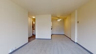 This single-floor residence at 2233 N Summit Ave in Milwaukee's vibrant East Side neighborhood offers a well-organized and functional layout. The spacious living area is finished with plush carpet, blue-accented baseboards, and a ceiling fan, creating a comfortable and airy atmosphere. A large window allows natural light to fill the room while offering views of the surrounding urban greenery and cityscape.

The kitchen is efficiently designed, featuring white cabinetry with dark countertops, a white tile backsplash, track lighting, and white appliances including a range and refrigerator. The kitchen transitions seamlessly into the living space, making it ideal for everyday living.

The bedroom is generously sized, carpeted, and equipped with a ceiling fan and a window that frames outdoor views of neighboring architecture and mature trees. A louvered bifold closet door provides practical storage.

The bathroom is clean and well-appointed, with a tiled tub/shower combination, a white vanity with a granite-style countertop, a mirrored medicine cabinet, and tasteful tile flooring. A hallway with hardwood-style flooring connects the main living areas, adding a warm contrast to the carpeted rooms throughout the unit.