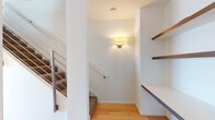This well-appointed two-floor space combines modern design with practical functionality across its layout. The kitchen is a standout feature, outfitted with warm wood-tone cabinetry paired with crisp white upper cabinets, a stainless steel backsplash, and a full suite of stainless steel appliances including a gas range, dishwasher, built-in microwave, and a full-size refrigerator. A central island with a clean countertop provides additional workspace, while pendant lighting adds a polished finishing touch. Light hardwood flooring runs through the kitchen and connecting areas, enhancing the bright, open feel.

The bathrooms are finished in a contemporary style. The full bathroom features floor-to-ceiling white subway tile surrounding a soaking tub with overhead shower, built-in wall shelving, and a floating vanity with clean-lined cabinetry. A separate half bath provides additional convenience with hardwood flooring and chrome fixtures.

The staircase connecting the two floors is fitted with a modern steel railing and carpeted treads, accompanied by a wall sconce and integrated built-in shelving — a practical yet stylish transition between levels. The bedrooms offer carpeted flooring and light-filled interiors, with one room featuring a skylight that draws in natural overhead light, creating a serene and airy atmosphere. The overall design palette is neutral and cohesive throughout.