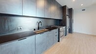 Located at 3675 Keystone Avenue in the Palms neighborhood of Los Angeles, this contemporary single-floor unit showcases a cohesive modern design throughout. Light wood flooring runs consistently across the living areas and bedroom, creating a warm, unified aesthetic that contrasts elegantly with the bold, darker accents found in the kitchen.

The kitchen is a standout feature, outfitted with floor-to-ceiling cabinetry in a dark, textured finish paired with matching dark countertops and a coordinating backsplash. Stainless steel appliances, including a gas range and a full-size refrigerator, are integrated seamlessly into the design. A deep undermount sink with a matte black faucet adds a refined, industrial touch.

The living area is open and bright, benefiting from large sliding glass doors that lead to an outdoor space with views of the surrounding neighborhood. An additional bedroom includes a ceiling fan and a large window that invites natural light and views of nearby architecture.

Two bathrooms are finished in a clean, contemporary style featuring terrazzo-style flooring and wall surrounds, wall-mounted vanities, bold black-framed mirrors, and tub-shower combinations enclosed by sleek black-framed sliding glass doors. Recessed lighting and clean white walls complete the polished, minimalist atmosphere throughout the unit.