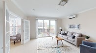 This well-designed two-floor residence offers a thoughtful layout filled with natural light and contemporary finishes throughout. The main living area is bright and welcoming, featuring crown molding, plush carpeting, and large sliding glass doors that open onto a private balcony with views of the surrounding neighborhood and lush greenery. A wall-mounted mini-split system ensures year-round comfort. A charming French door connects to an additional sitting room, also with balcony access, providing a versatile space for relaxation or entertaining.

The kitchen is a standout feature, outfitted with crisp white shaker cabinetry, granite countertops, a grey subway tile backsplash, and pendant lighting — offering both style and ample storage. A dedicated home office with soft carpet and neutral walls provides a quiet retreat for focused work.

The bedrooms are generously proportioned, each featuring plush carpeting, sliding glass door access to outdoor spaces, and individual mini-split climate control. The primary bedroom includes a spacious walk-in closet with built-in shelving. The bathroom is finished with wood-look luxury vinyl flooring, a white vanity with quartz countertop, and a full tub-shower combination. Throughout, the neutral palette and clean architectural lines create a calm, cohesive living environment.
