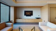 Located at 2500 Fulton Place in Reston, Virginia, this single-floor space presents a cohesive, contemporary design that integrates multiple functional zones within an open, flowing layout. Large-format tile flooring anchors the space, while recessed lighting and tray ceilings add architectural depth throughout.

The lounge area is furnished with plush, rust-orange accent chairs arranged around a sculptural round coffee table, complemented by warm wood-paneled walls and steel-framed glass partitions that allow light to pass freely between zones. A dedicated media wall features built-in light wood cabinetry, a wall-mounted flat-screen display, and integrated sound equipment, creating a polished, tech-ready environment.

The dining area accommodates a generous gathering around a sleek dark table paired with contemporary seating, illuminated by pendant track lighting overhead. Floor-to-ceiling windows line this zone, offering expansive views of the surrounding wooded landscape and flooding the space with natural light.

The kitchen presents a refined aesthetic with light wood cabinetry, marble slab open shelving with integrated under-lighting, a stone countertop, and a panel-ready refrigerator. A large window provides direct natural light, enhancing the clean, minimalist character of this well-appointed space.