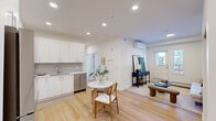 Located at 76 Shawnee Blvd SW in Calgary, this thoughtfully designed unit maximizes its compact footprint across a single floor, accommodating three bedrooms and two full bathrooms. The open-concept kitchen and living area anchors the layout, featuring a bright, contemporary kitchen outfitted with white flat-panel cabinetry extending to the ceiling, stainless steel appliances including a refrigerator, electric range, and dishwasher, white countertops, and light wood-tone flooring that carries throughout the entire unit. Recessed lighting illuminates the kitchen, which comfortably fits a small dining table. The living room is clean and understated, with white walls and a simple, functional layout. The primary bedroom accommodates a full-sized bed and benefits from a large window that allows natural light to fill the room, with a baseboard heating unit beneath. The two bathrooms maintain the unit's clean aesthetic — one features a shower-tub combination with white surround, and the other a curtained shower. A dedicated in-suite laundry closet houses stacked washer and dryer units. A private balcony offers views of the surrounding residential neighbourhood.
