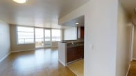 Unit 1122 is a well-appointed 2-bedroom, 2-bathroom residence that offers a generous and functional floor plan across a single level. The open-concept layout seamlessly connects the kitchen and living areas, creating a bright and welcoming atmosphere ideal for both everyday living and entertaining.

The kitchen features rich, dark wood cabinetry, granite countertops, and a peninsula with a built-in sink that serves as a natural dividing point between the kitchen and the main living space. The warm hardwood flooring flows throughout, adding a cohesive and polished feel to the interior.

The living area is bathed in natural light, thanks to expansive floor-to-ceiling windows that frame impressive views of the surrounding cityscape and waterfront beyond. A private balcony accessible from the living room extends the living space outdoors and provides a perfect vantage point to enjoy the scenic surroundings.

The clean, neutral color palette throughout the unit enhances the sense of openness and allows for versatile interior styling. With two full bathrooms and two well-proportioned bedrooms, this residence offers both comfort and practicality. The overall ambiance is modern and understated, making Unit 1122 a refined urban living experience.