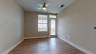 This single-story space offers a well-designed layout with a clean, contemporary aesthetic throughout. The kitchen serves as a central highlight, featuring sleek white cabinetry extending to the ceiling, a white subway tile backsplash, stainless steel appliances including a range and built-in microwave, and a spacious island topped with granite countertops and an undermount sink. Pendant lighting above the island adds a polished finishing touch, while light hardwood-style flooring ties the space together.

The living area is bright and open, benefiting from natural light streaming through a large window and a glass-paneled exterior door that opens to an outdoor area with visible balcony railings. A ceiling fan overhead provides both comfort and function. The neutral warm-beige wall tones create a calm, cohesive atmosphere throughout.

The bedrooms are carpeted and generously proportioned, each featuring ceiling fans and access to adjacent areas. The bathroom is finished with a granite-topped white vanity, brushed nickel hardware, hardwood-style flooring, and a full tub-shower combination with white tile surround. Overall, the space presents a modern, well-appointed interior with consistent finishes throughout.